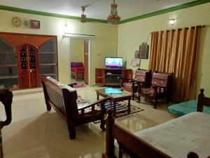 ein Wohnzimmer mit Möbeln und einem Flachbild-TV in der Unterkunft soms estate stay in Madikeri