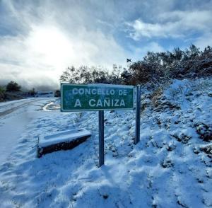 Casa Rural Cabo de Aráns في Oroso: وجود لافتة على الشارع الأخضر على جانب الطريق المغطى بالثلوج