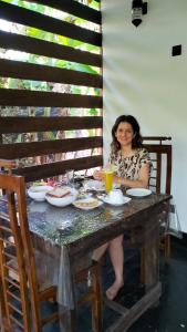 a woman sitting at a table with food at Yashi's Place Sigiriya in Sigiriya