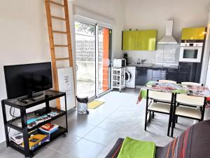 een woonkamer met een televisie en een keuken bij Case Couleur proche de la mer in Brem-Sur-Mer