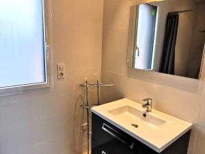een badkamer met een wastafel en een spiegel bij Case Couleur proche de la mer in Brem-Sur-Mer