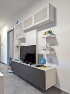 a living room with a tv and white walls at I colori della Sicilia in Cinisi