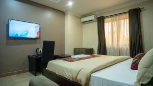 ラゴスにあるKABACHI STACKのベッド1台、薄型テレビが備わるホテルルームです。