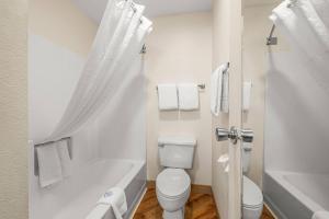 a white bathroom with a toilet and a bath tub at La Quinta by Wyndham Tampa Brandon West in Tampa