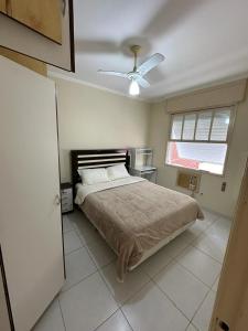 a bedroom with a bed and a ceiling fan at Apartamento na Praia in Guarujá
