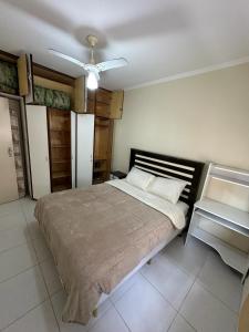 a bedroom with a large bed and a ceiling fan at Apartamento na Praia in Guarujá