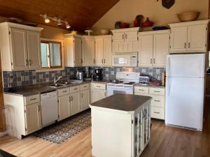 a kitchen with white cabinets and a white refrigerator at Sunset Lakehouse, cozy cottage in Miller Lake