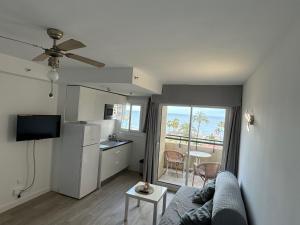 Una sala de estar con un sofá y una cocina. en TORREMOLINOS CARIHUELA 1ª LINEA PLAYA, en Torremolinos