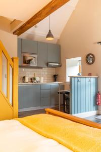 a kitchen with gray cabinets and a yellow bed in a room at Captains Lookout (Studio apartment) in Brecon