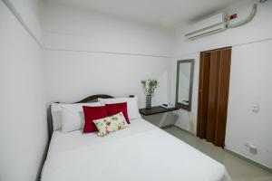 a bedroom with a white bed with red pillows at hospedaje rosa blanca in Cartagena de Indias