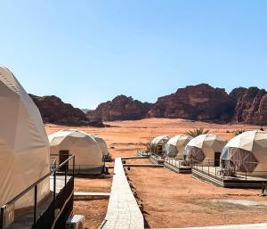 a row of tents in the desert with mountains at Hasan Zawaideh Camp in Wadi Rum