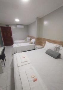a hotel room with two beds and a chair at Pousada Chapada do Araripe in Araripina