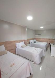a hotel room with two beds with white sheets at Pousada Chapada do Araripe in Araripina +24 photos