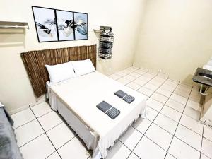 a bedroom with a bed in a white tiled room at Loft Familiar BR-Aeroporto 4 in Uberlândia