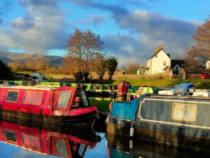 a boat sitting in the water next to a house at Captains Lookout (Studio apartment) in Brecon