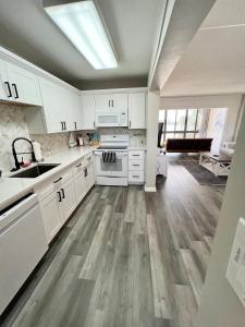 uma cozinha com armários brancos e pisos em madeira em Wondrous Waterfront Condo w/ Pool & Washer/Dryer em Fort Walton Beach