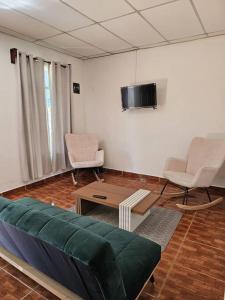 uma sala de estar com um sofá e duas cadeiras e uma televisão em La Casa de la Gaviota em Siguatepeque