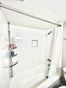 a white bathroom with a tub and a sink at Wondrous Waterfront Condo w/ Pool & Washer/Dryer in Fort Walton Beach