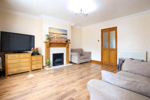 a living room with a television and a fireplace at 3 bedrooms Sleeps 8 Self Catering House Near California Cliffs and Great Yarmouth Beach,Norfolk in Earlham