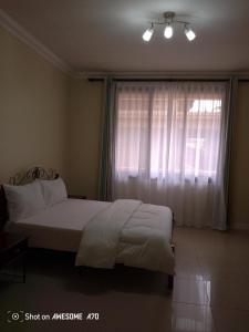 a bedroom with a white bed and a window at Cozy 3BR w/pool & gym in Dar es Salaam