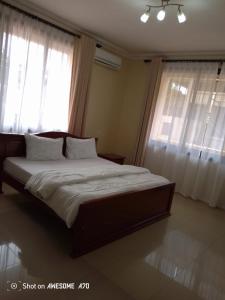 a bedroom with a large bed with two windows at Cozy 3BR w/pool & gym in Dar es Salaam