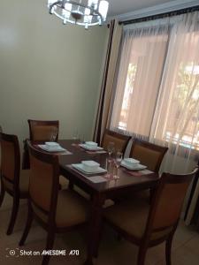 a dining room table with chairs and a wooden table and a window at Cozy 3BR w/pool & gym in Dar es Salaam