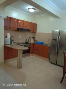 a kitchen with wooden cabinets and a stainless steel refrigerator at Cozy 3BR w/pool & gym in Dar es Salaam