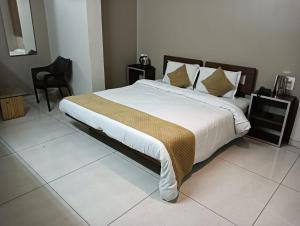 a bedroom with a large bed and a chair at HOTEL INDRANI in Chittaurgarh