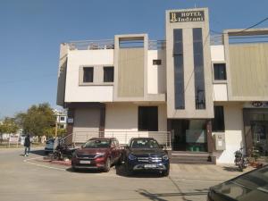 two cars parked in a parking lot in front of a building at HOTEL INDRANI in Chittaurgarh