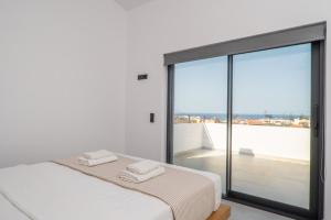 a white room with a bed and a large window at Montis villa in Daratso