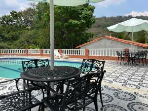 una mesa con sombrilla y sillas junto a una piscina en Hotel Campestre La Quinta del Muelle, en San Gil