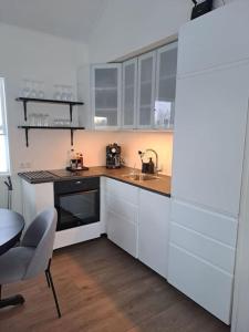 a kitchen with white cabinets and a sink and a table at Nýlegur sumarbústaður/friðsæld in Mosfellsbær