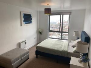 a bedroom with a bed and a large window at EEJs Beautiful 2 bed Apartment - Sheffield centre in Sheffield