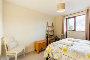 a bedroom with a bed and a chair and a window at Stratford House - Perfect for a get together in Upton Snodsbury