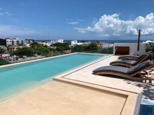a swimming pool with lounge chairs on a building at Nuevo y lujoso estudio céntrico in Playa del Carmen