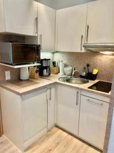a kitchen with white cabinets and a sink and a microwave at Inselliebe Norderney in Norderney