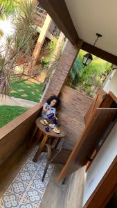 a woman sitting at a table in a house at Pousada Adega Cipo in Serra do Cipo