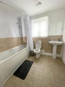 a bathroom with a tub and a toilet and a sink at Modern 2 bed city apartment with private parking in Swansea