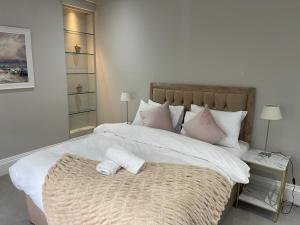 a bedroom with a large white bed with pink pillows at Falcon suits in London