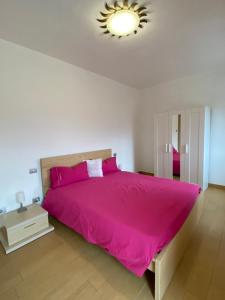 a bedroom with a large bed with a pink bedspread at Casa Carmen Apartment Lake Como in Dongo