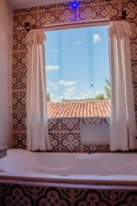 a window with white curtains and a tile roof at Pousada Adega Cipo in Serra do Cipo