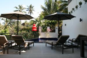 a patio with chairs and umbrellas next to a pool at Rumah Riang in Mayong