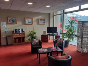 a waiting room with chairs and a table and a tv at H&ocirc;tel Les Gens De Mer Dunkerque by Popinns in Dunkerque
