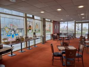 ein Esszimmer mit Tischen und Stühlen und Fenstern in der Unterkunft Hôtel Les Gens De Mer Dunkerque by Popinns in Dunkerque