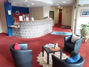 a lobby with chairs and a table and a counter at H&ocirc;tel Les Gens De Mer Dunkerque by Popinns in Dunkerque
