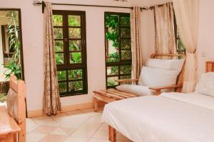 a bedroom with a bed and a chair and windows at Ngorongoro Camp and Lodge in Karatu