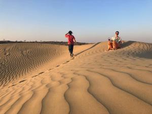 three people sitting on the sand dunes in the desert at Marigold Homestay in Jaisalmer