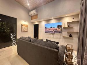 ein Wohnzimmer mit einem Sofa und einem TV an der Wand in der Unterkunft GoldenView+ Aire acondicionado+Jacuzzi (a 15 km de Monteverde) in Monteverde Costa Rica