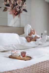 une femme qui se couche dans le lit avec un plateau avec un bol de nourriture dans l'établissement 7 SKY UDINE, à Udine