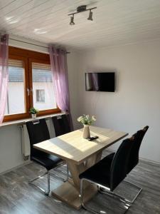 a dining room table with black chairs and a television at Pension Unterreichenbach in Schwabach
